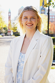 A headshot photo of Mariya Yasinovska with a clocktower and trees in the background.