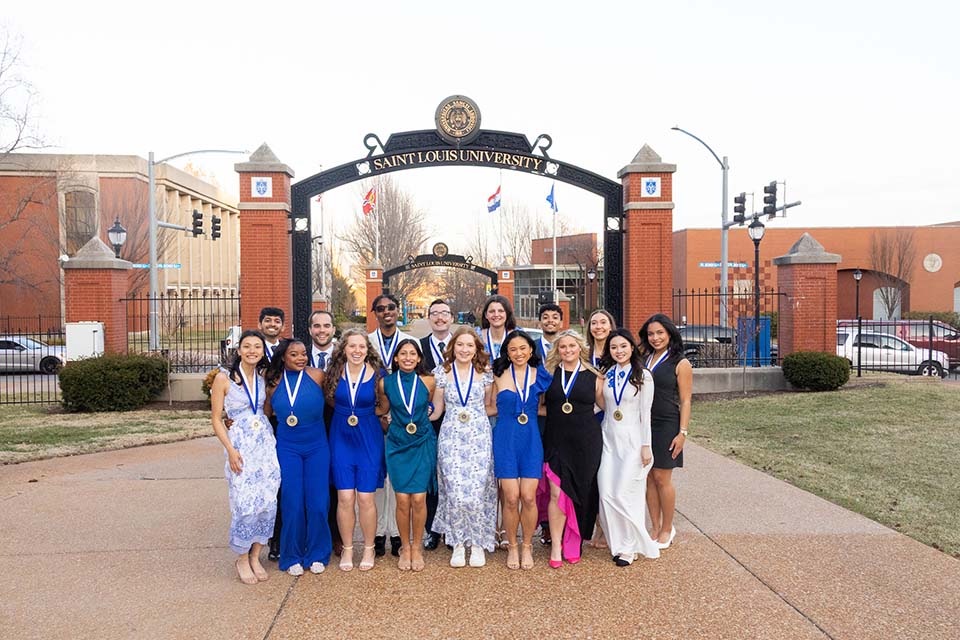 Spirit of the Billiken A large group of students dressed nicely and with medals around their neck pose for a photo outside on SLU's campus.
