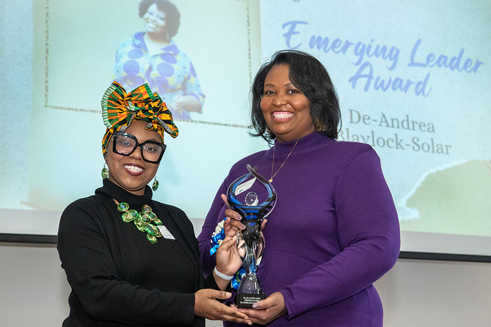 Two women pose for a photo holding an award.