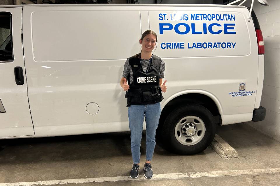 student poses in front of police crime laboratory van student poses in front of police crime laboratory van