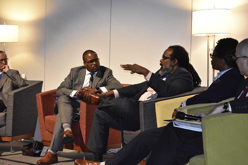 Panelists sit in arm chairs while discussing a topic.