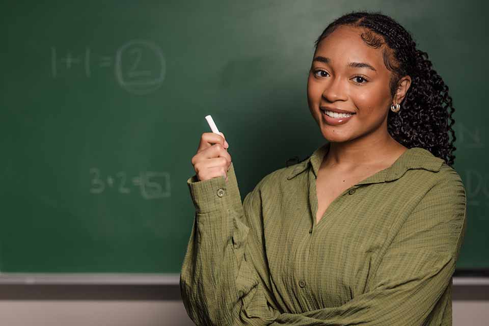 Camille Fuller poses for a photo in front of a chalk board.