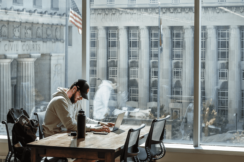 Male student studies at desk in library. Civil courts building can be seen outside the window.