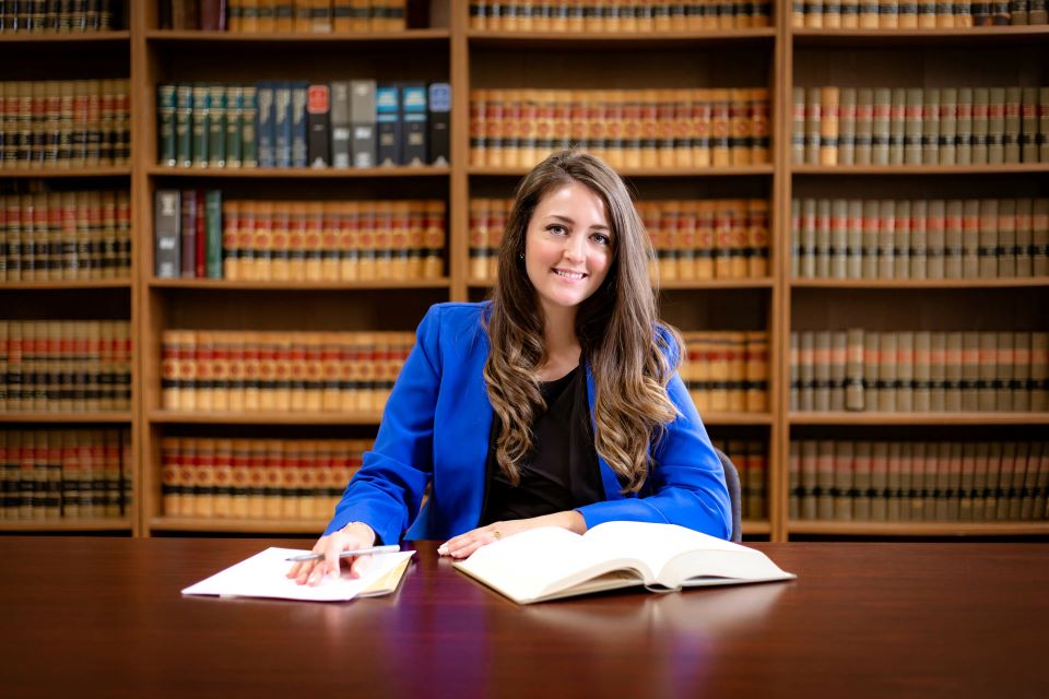Letitia Wiggins poses at a table with books open, in front of shelves of law books.