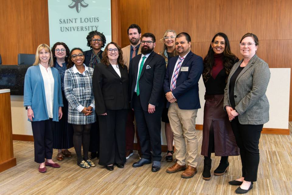Group photo of 2025 Health Law Symposium participants A group of 11 participants pose for a photo at the fron tof a lecture hall.