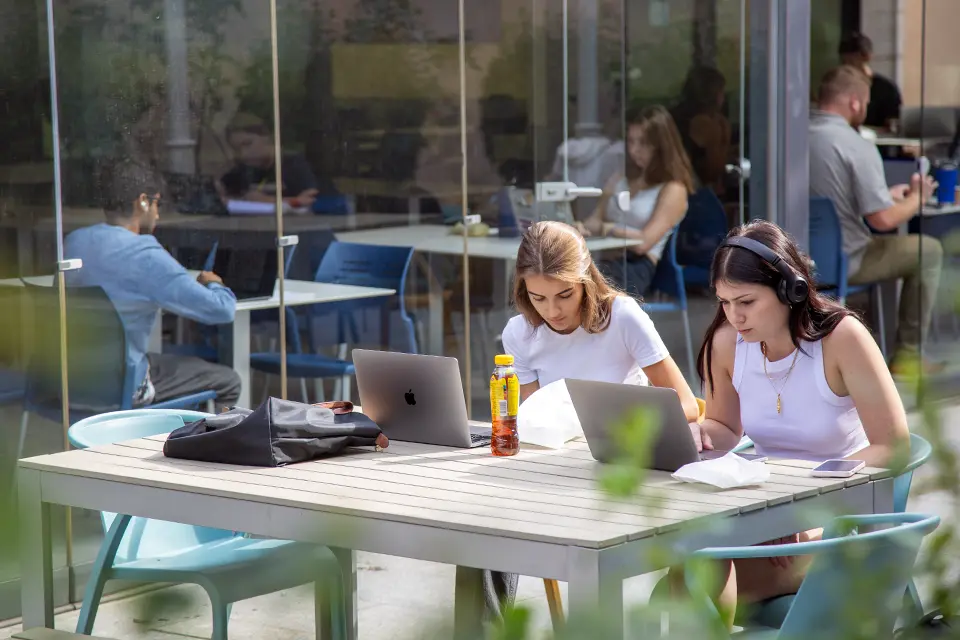 Two students with laptops at SIH patio