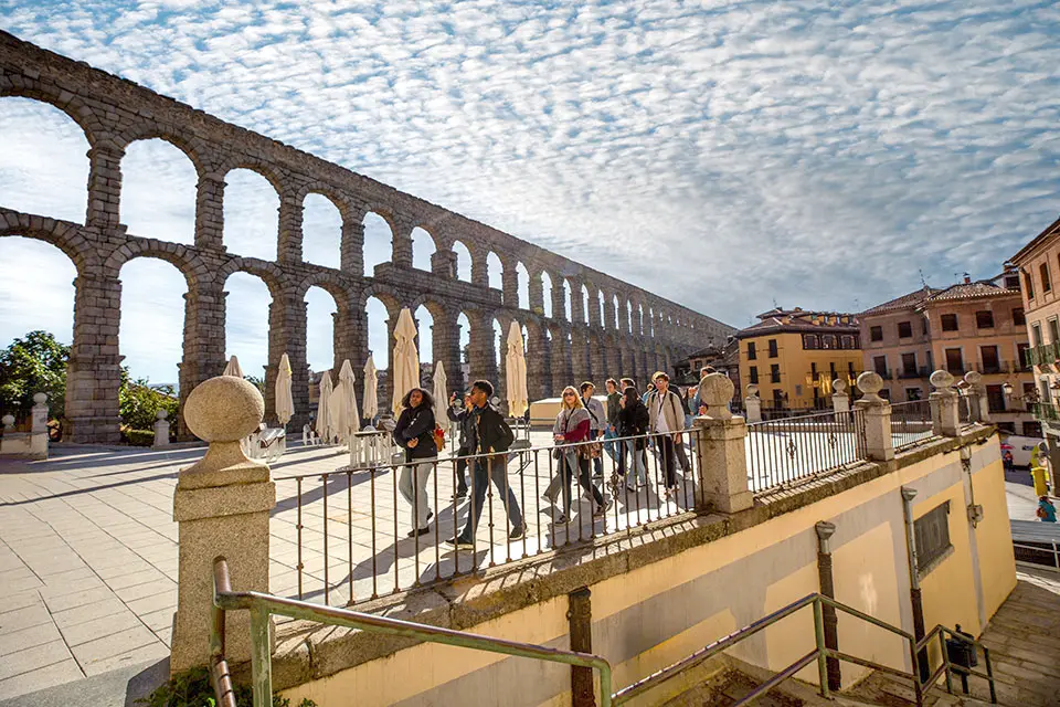 A Roman aqueduct with arches made of granite brick stretches itself next to a town.