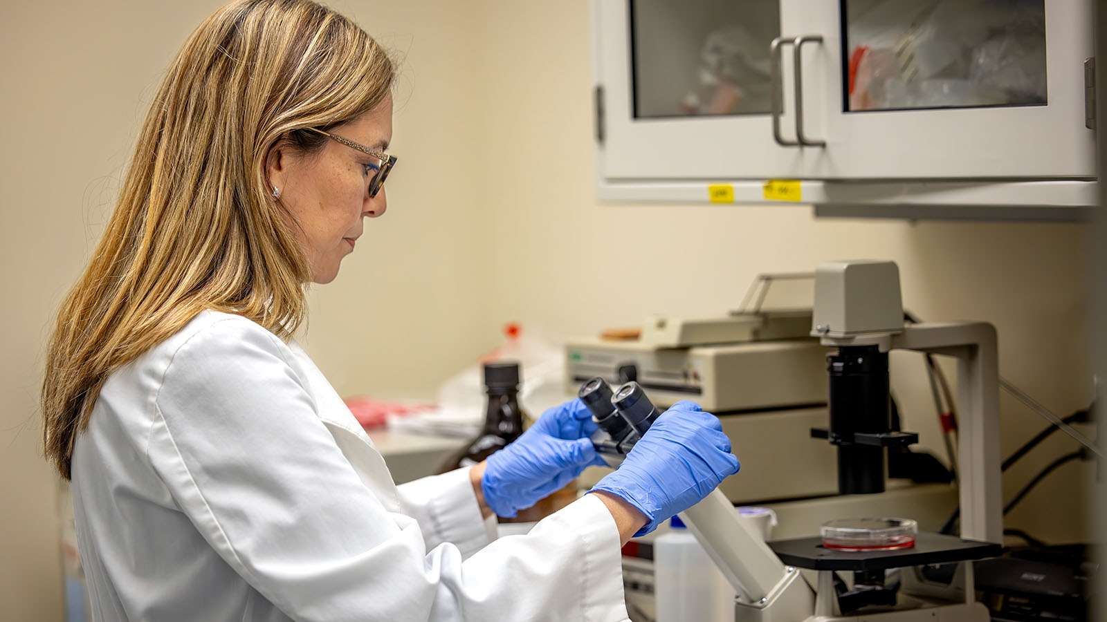Andrea Montano adjusts a microcope in a lab.