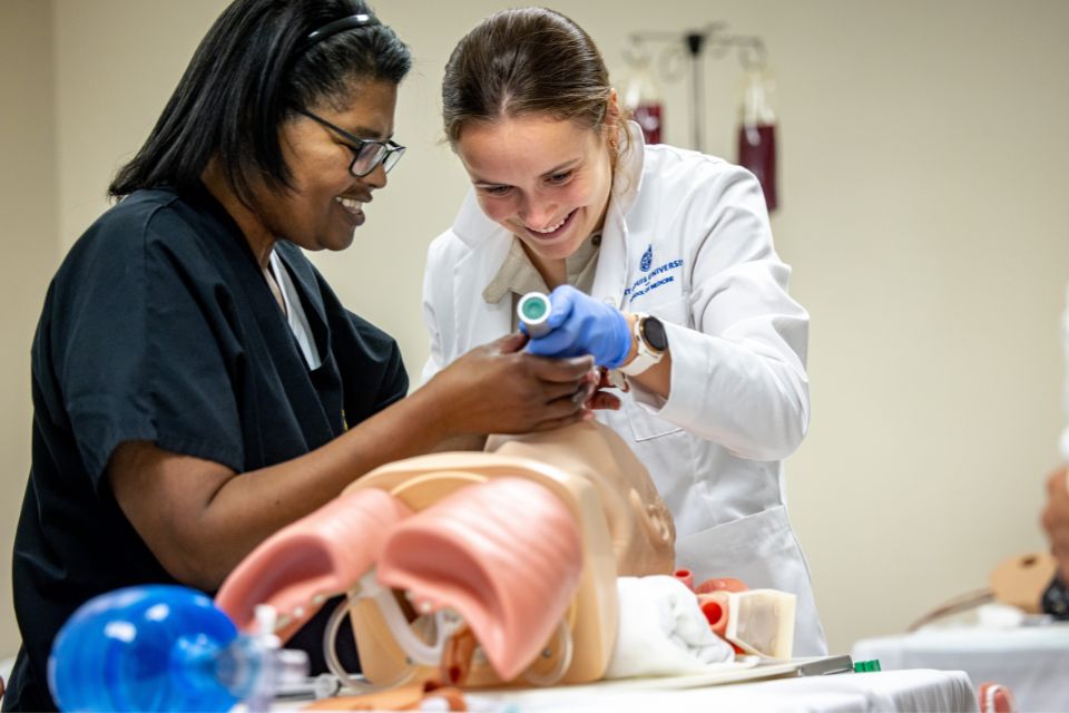 A medical student and instructor practice an intubation procedure on a mannequin.