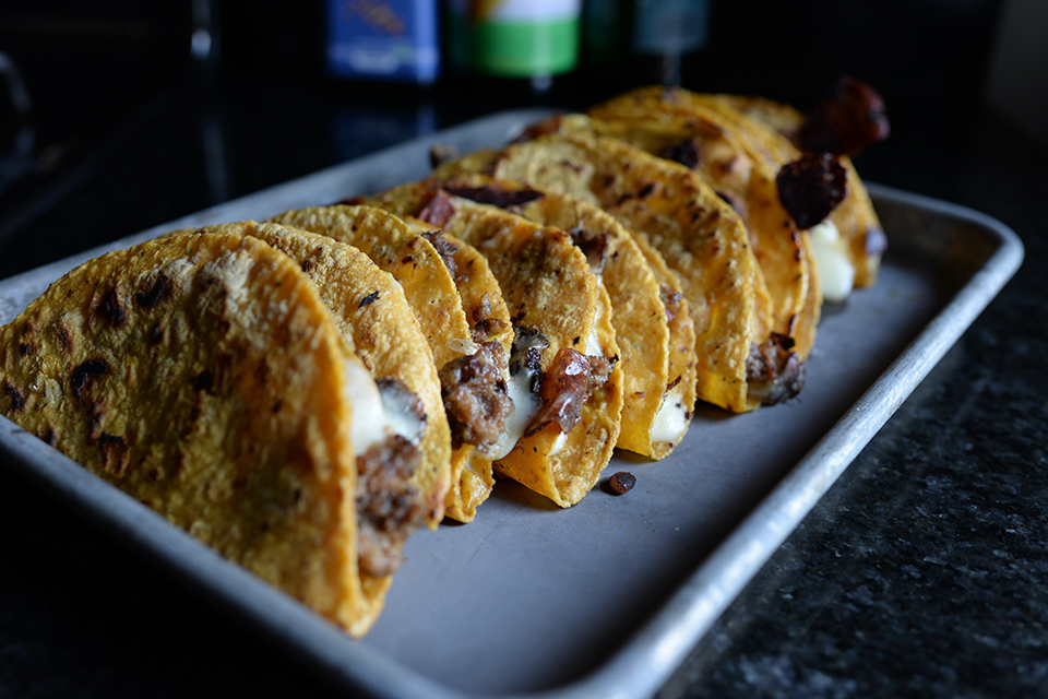 A row of hard-shell tacos on a tray.