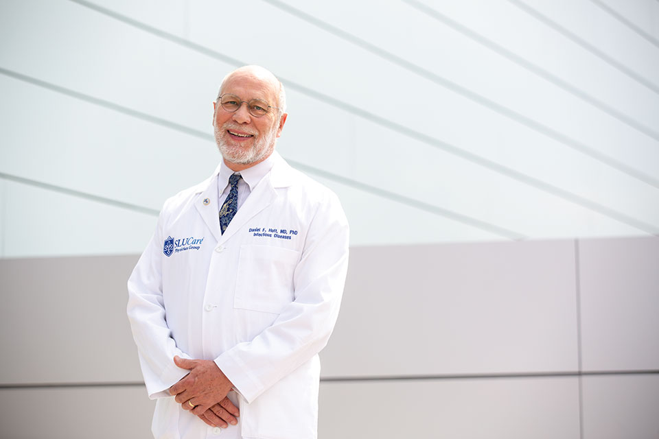 Daniel Hoft, M.D., Ph.D., poses in a white lab coat outdoors on a bright, sunny day.