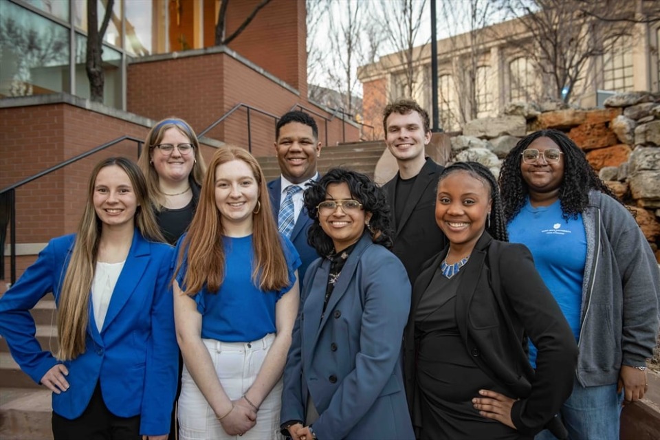 Board members stand in two rows outdoors on the SLU campus