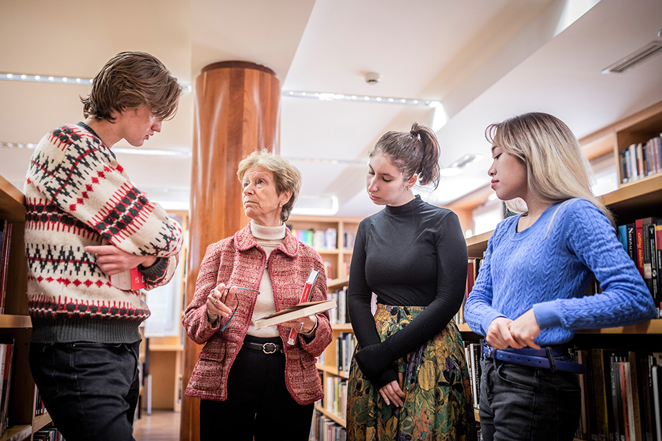 A professor discusses a book with students in a library